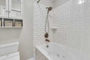 Primary bathroom with tiled shower / bath combo and toilet