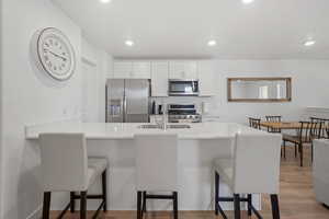 Kitchen with white cabinetry, kitchen peninsula, appliances with stainless steel finishes, and a kitchen breakfast bar