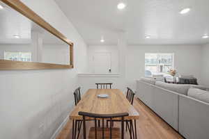 Dining area with a textured ceiling, a healthy amount of sunlight, and light wood-type flooring