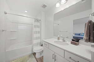 Full bathroom featuring vanity, toilet, shower / bathtub combination with curtain, and wood-type flooring