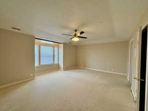 Carpeted empty room with ceiling fan and a textured ceiling