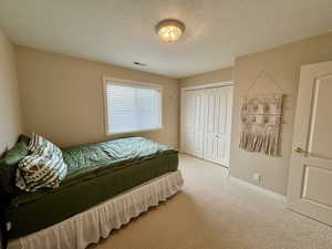 Bedroom with carpet floors, a textured ceiling, and a closet