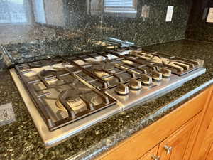 Details featuring tasteful backsplash, dark stone countertops, and stainless steel gas cooktop