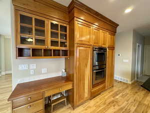 Kitchen featuring light hardwood / wood-style floors, double oven, and built in desk