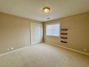 Unfurnished bedroom with a textured ceiling, carpet floors, and a closet