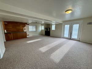 Unfurnished living room with plenty of natural light, a textured ceiling, and carpet