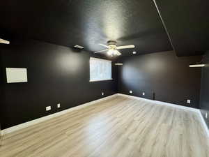 Empty room with light hardwood / wood-style floors, a textured ceiling, and ceiling fan