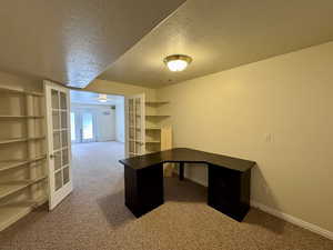 Unfurnished office with a textured ceiling, carpet, and french doors