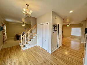 Interior space with ceiling fan with notable chandelier and light wood-type flooring