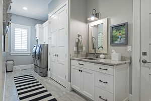 Bathroom featuring washing machine and dryer, tile patterned flooring, and vanity