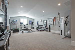 Workout room with light carpet, a textured ceiling, and vaulted ceiling