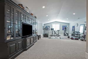 Workout room featuring vaulted ceiling and carpet floors