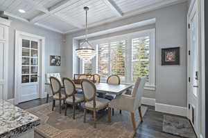 Dining space with a notable chandelier, beam ceiling, and dark hardwood / wood-style flooring