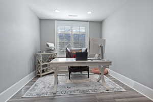 Home office with dark hardwood / wood-style flooring