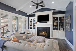 Living room with ceiling fan, dark wood-type flooring, and lofted ceiling with beams