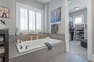 Bathroom with tiled tub and tile patterned floors