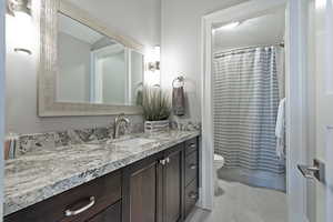 Bathroom with tile patterned floors, toilet, vanity, and a shower with curtain