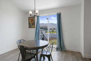 Dining area featuring wood-type flooring, a mountain view, a healthy amount of sunlight, and an inviting chandelier