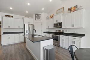 Kitchen with sink, white cabinets, an island with sink, lofted ceiling, and stainless steel appliances