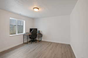 Office space featuring light wood-type flooring and a textured ceiling