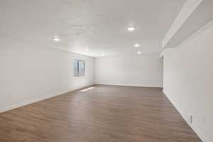 Empty room with a textured ceiling and dark hardwood / wood-style floors