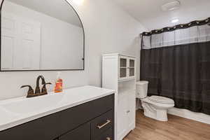 Full bathroom featuring hardwood / wood-style flooring, toilet, vanity, and shower / tub combo