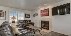 Living room with light colored carpet and a tile fireplace