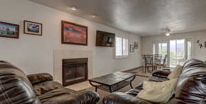 Living room featuring a tiled fireplace, plenty of natural light, and a textured ceiling