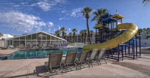 View of swimming pool featuring a playground, a water slide, and a patio