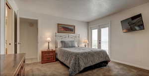 Bedroom with carpet, access to outside, and a textured ceiling