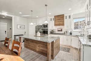 Kitchen with pendant lighting, sink, white cabinetry, a center island, and stainless steel appliances