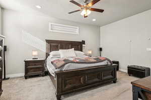 Bedroom featuring a textured ceiling, light colored carpet, and ceiling fan