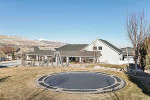 Back of house featuring a mountain view, a yard, and a trampoline