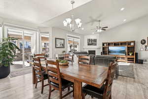 Dining space featuring vaulted ceiling, a healthy amount of sunlight, light hardwood / wood-style floors, and a fireplace