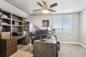 Carpeted office with vaulted ceiling, a healthy amount of sunlight, and a textured ceiling