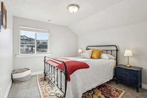 Bedroom with carpet floors, a textured ceiling, and lofted ceiling