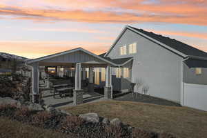 Back house at dusk featuring a patio area and a yard