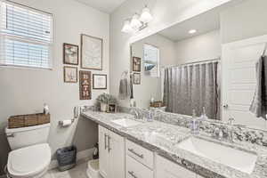 Bathroom with plenty of natural light, toilet, tile patterned flooring, and vanity