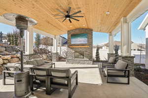 View of patio / terrace with ceiling fan and an outdoor living space with a fireplace