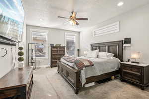 Carpeted bedroom with ceiling fan and a textured ceiling