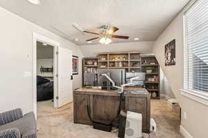 Carpeted home office featuring ceiling fan, a textured ceiling, and lofted ceiling