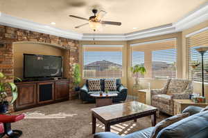 Living room with ceiling fan, light carpet, and a tray ceiling