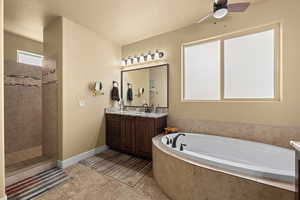 Bathroom featuring a textured ceiling, shower with separate bathtub, ceiling fan, and vanity