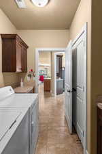 Laundry room with cabinets, independent washer and dryer, and light tile patterned flooring