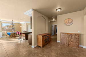 Hall featuring a textured ceiling, crown molding, and an inviting chandelier