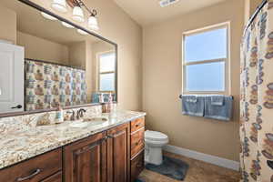 Bathroom with plenty of natural light, tile patterned floors, toilet, and vanity