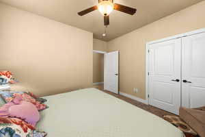 Carpeted bedroom with ceiling fan and a closet