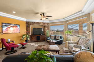 Living room with ceiling fan, carpet, crown molding, and a raised ceiling