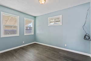 Unfurnished room with dark wood-type flooring and a textured ceiling