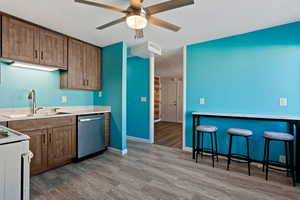 Kitchen featuring white electric stove, light hardwood / wood-style floors, sink, stainless steel dishwasher, and a breakfast bar area